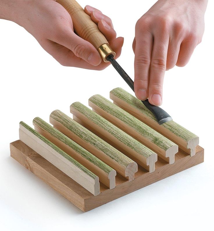 a person is using a knife to cut up wood strips on a board with a wooden mallet