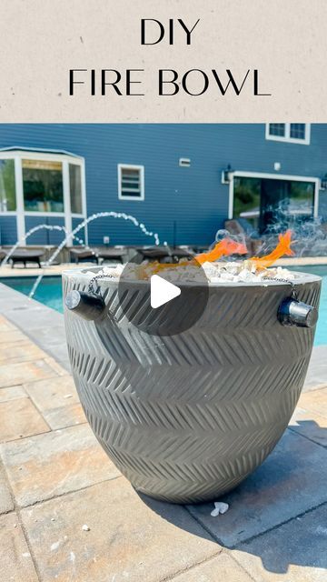 a fire bowl sitting on top of a patio next to a swimming pool with the words diy fire bowl