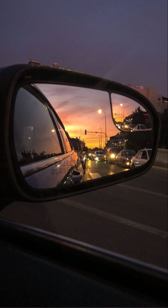 the rear view mirror of a car with traffic in it at sunset or sunrise time