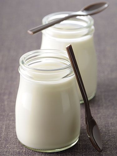 two glass jars filled with yogurt sitting on top of a purple tablecloth