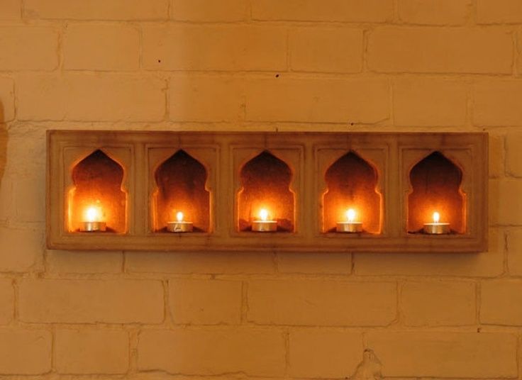 candles are lit in the middle of a wall with arches and niches on it