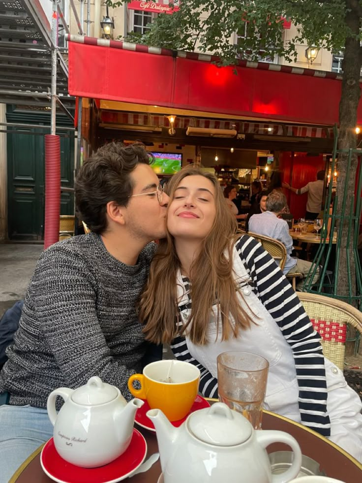 a man and woman kissing at an outdoor cafe