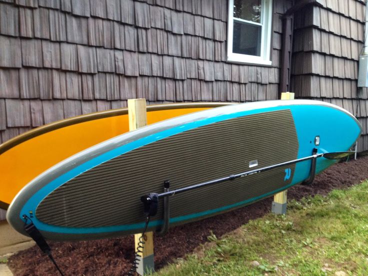 two surfboards are propped up against the side of a house in front of some grass