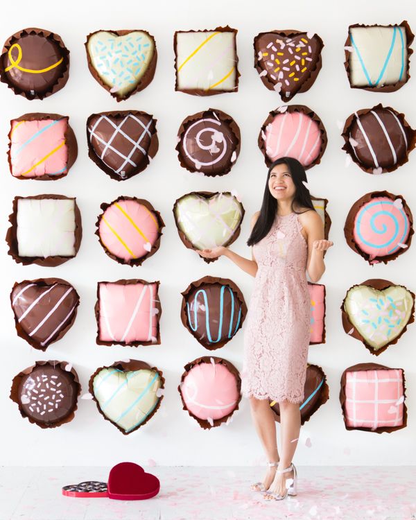 a woman holding a heart shaped plate in front of some decorated cookies on a wall