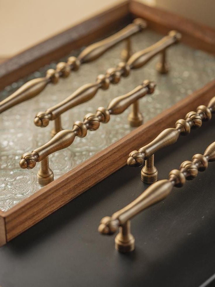 an old fashioned wooden and glass display case with brass knobs on the handles,