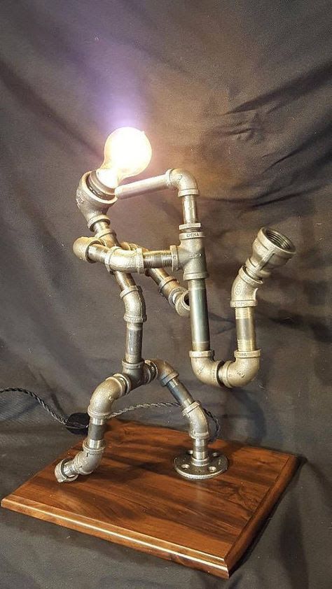 a lamp made out of pipes on top of a wooden board with a light bulb