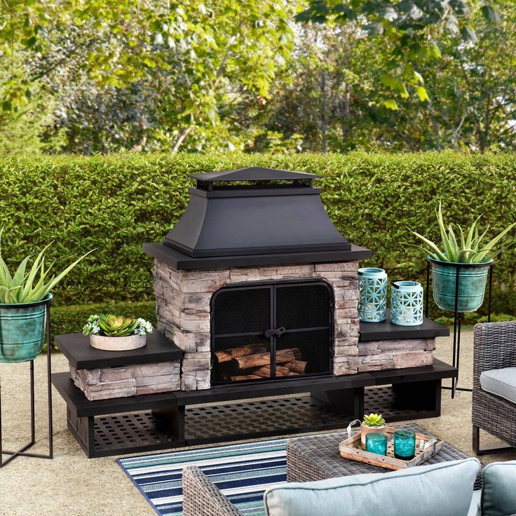 an outdoor fireplace surrounded by furniture and plants