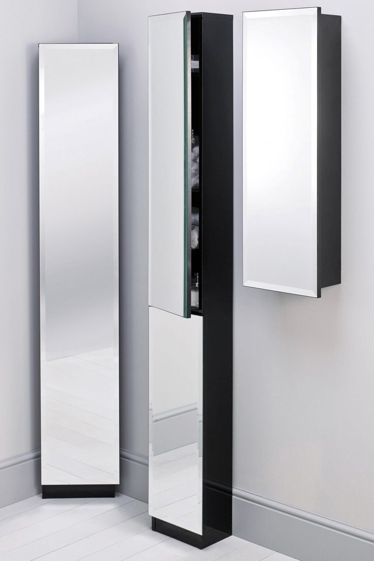 a tall black and white mirror next to a wall mounted cabinet in an empty room