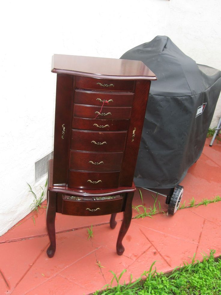 a wooden dresser sitting on top of a red tile floor next to a black grill