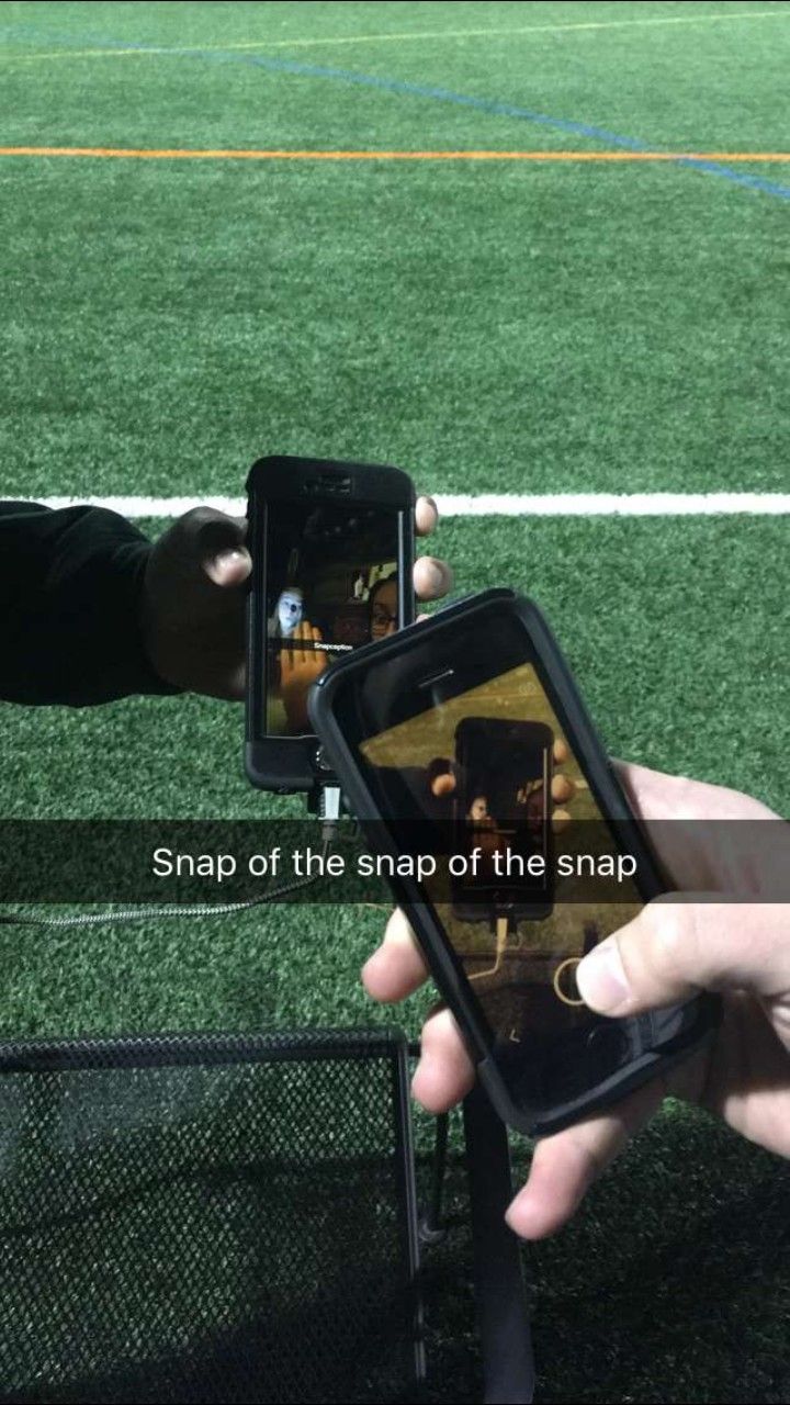 someone holding up their cell phone to take a photo on the field with another person