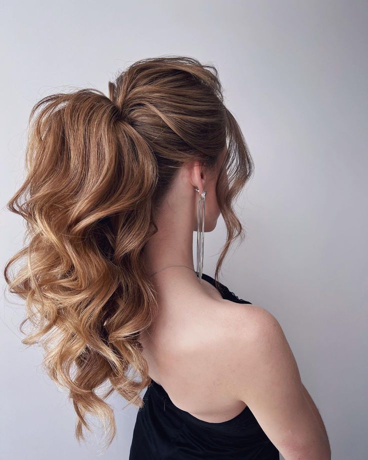 A high ponytail with voluminous curls and a teased crown creates a bold, statement look. The texture and height make this hairstyle perfect for formal events, giving off an air of confidence and glamour. Loose curls around the face soften the style. Messy Pony Hairstyles, Loose Curl Ponytail, Textured High Ponytail, High Ponytail Gala, High Ponytail With Curls, Ponytail Formal Hairstyles, Messy Curly Ponytail, High Pony Wedding Hair, Formal Ponytail Hairstyles