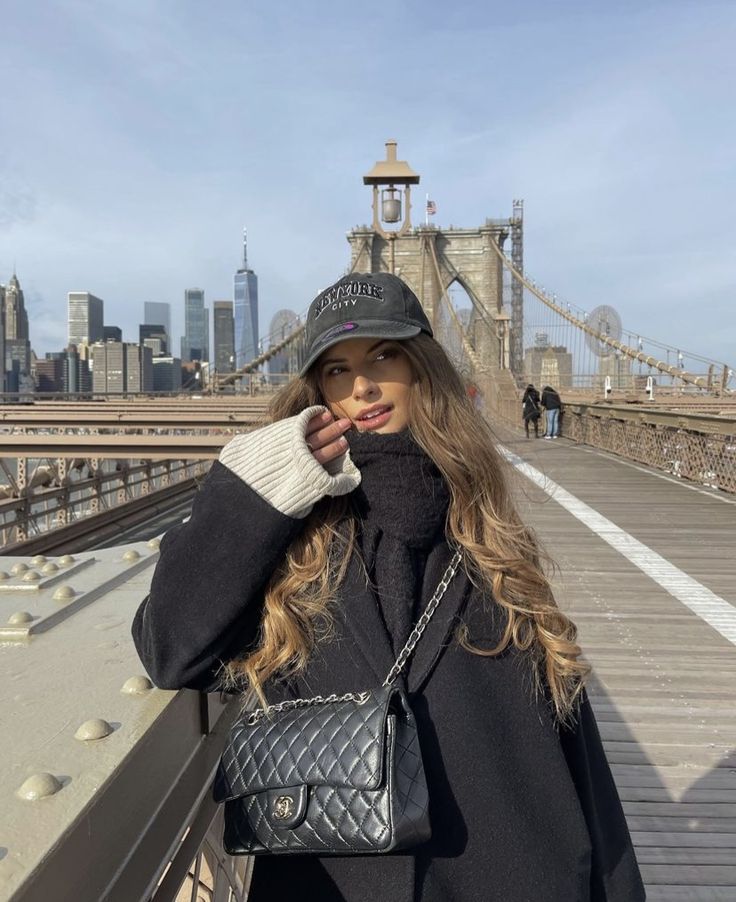 a woman is standing on a bridge with her hand in her pocket and looking at the camera