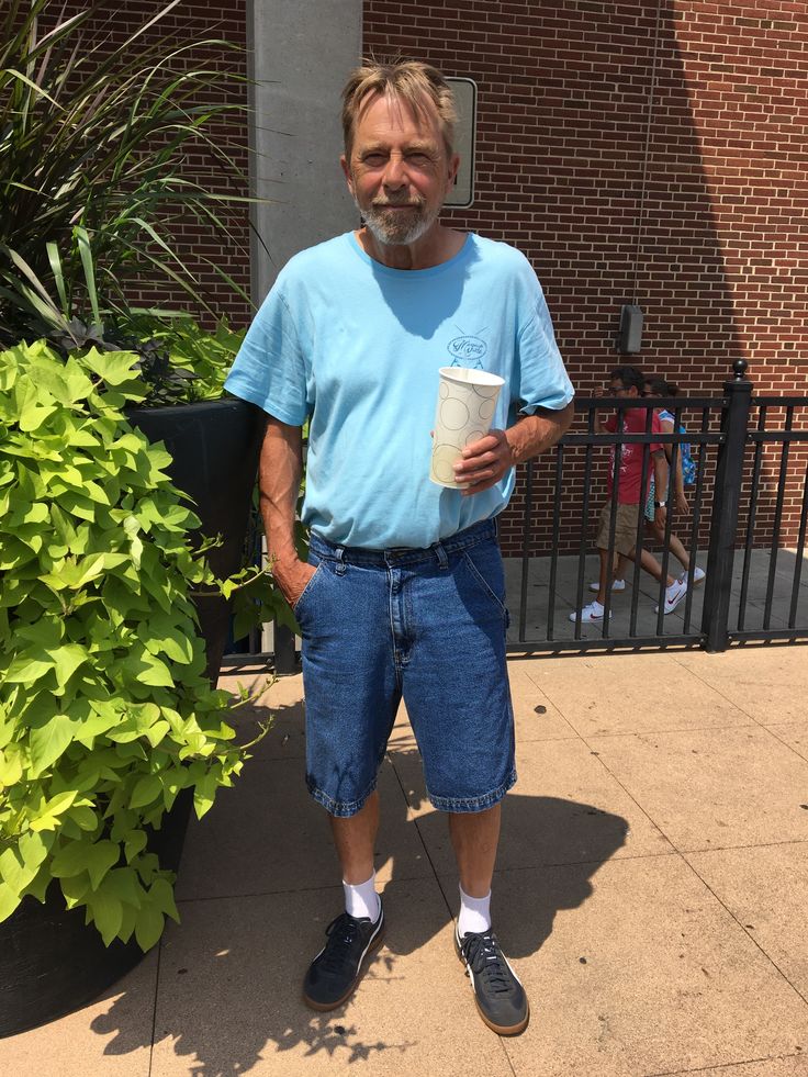 a man standing on the sidewalk holding a coffee cup