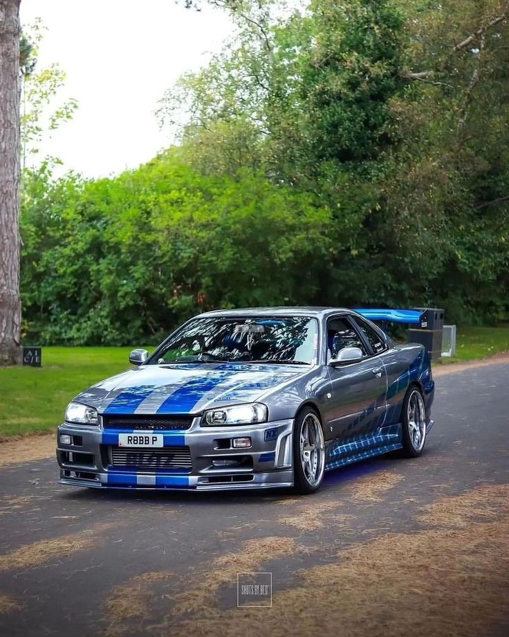 a blue and white car parked on the side of a road next to some trees