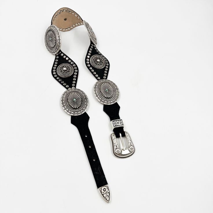 Indulge in the elegant and exclusive style with our Lyra Concho Belt. Made from luxurious black Italian leather, this western-style belt features intricate silver concho hardware and stud details. The silver buckle set adds the perfect finishing touch. Elevate any outfit and make a statement with this sophisticated accessory. Details: Smooth black Italian leather Silver plated buckle set and hardware Sourced in Italy Made in California Luxury Black Embroidered Belt, Western Black Embroidered Belt, Black Western Style Embroidered Belt, Black Western Belt Buckles With Silver Buckle, Antique Black Belt Buckles For Festivals, Western Black Belt Buckles With Silver Detail, Western Black Belt Buckles With Silver Buckle, Western Style Silver Belt Buckle, Western Black Belt Buckle With Belt