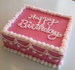 a pink birthday cake sitting on top of a table