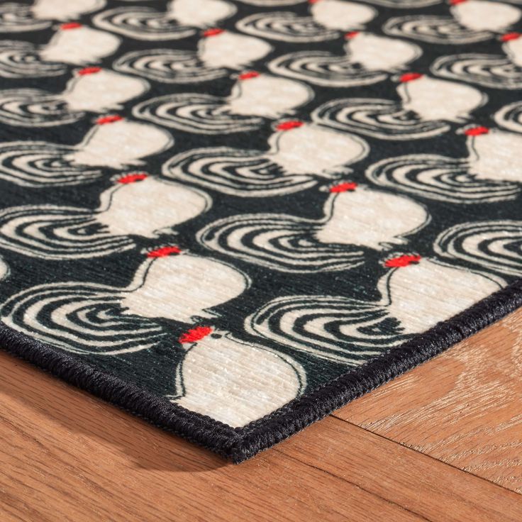 a black and white area rug with roosters on the front, sitting on top of a wooden floor