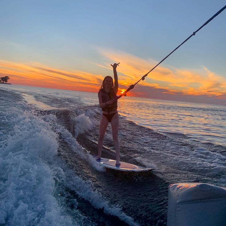 a woman on a surfboard in the water with her arms up as she rides