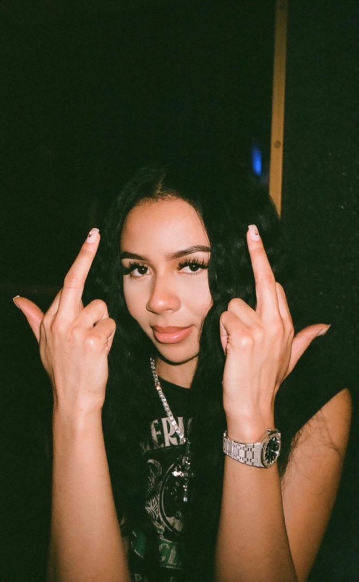 a woman with long black hair holding two fingers up