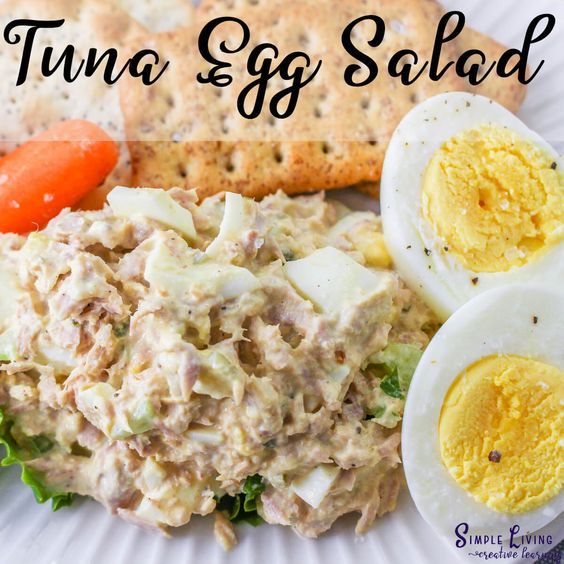 an egg salad on a plate with crackers, carrots and hard boiled eggs