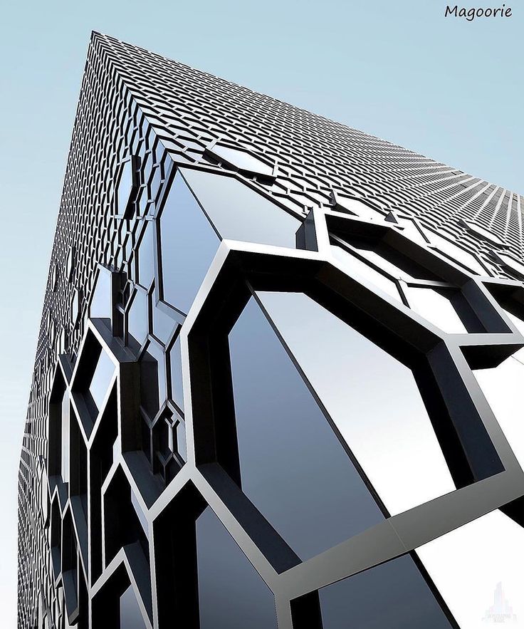 an abstract black and white building with geometric designs on the outside, against a blue sky