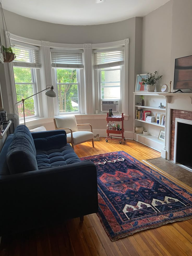 a living room filled with furniture and a large rug on top of a hard wood floor