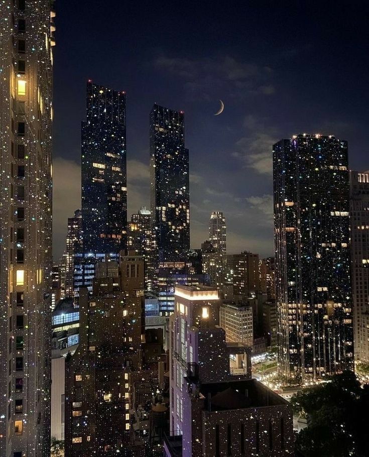 the city skyline is lit up at night, with skyscrapers in the foreground