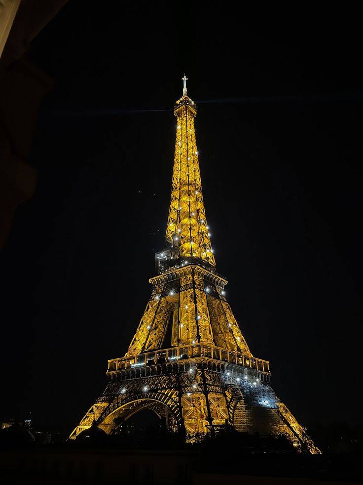 the eiffel tower lit up at night with lights on it's sides