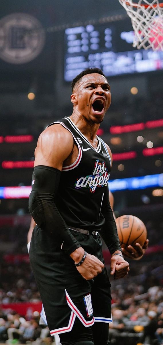 a man holding a basketball in his right hand and yelling at the ball he is about to dunk