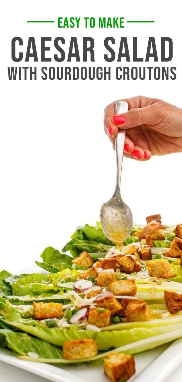 someone is spooning dressing from a plate with lettuce and croutons