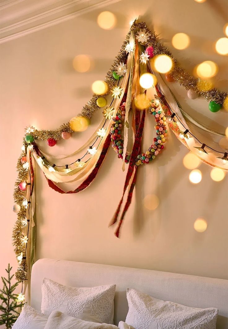 a bedroom decorated for christmas with lights on the headboard and garland hanging from the ceiling