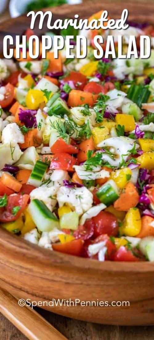 a wooden bowl filled with chopped salad on top of a table