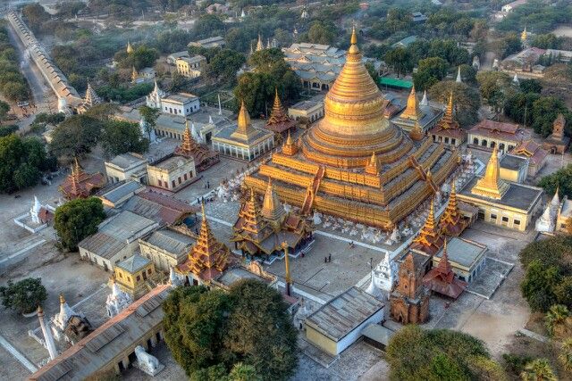 an aerial view of a golden pagoda in the middle of a town surrounded by trees