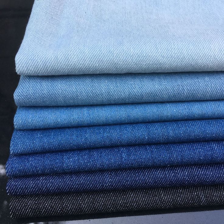 blue jeans stacked on top of each other in different sizes and colors, all folded neatly