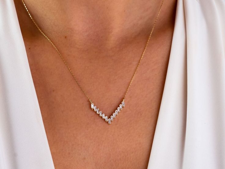 This 14K gold V-shaped necklace is a stunning and elegant piece of jewelry that would make a beautiful gift for any occasion. The CZ diamond chevron pendant is a unique and stylish design, featuring a minimalist geometric V-shaped charm that is encrusted with sparkling diamonds. This necklace would be a perfect gift for a loved one on Christmas, Father's Day, Mother's Day, Valentine's Day, an anniversary, or a birthday. It is also a great choice as a wedding necklace, as its sophisticated and ti Fine Jewelry Wedding Necklaces With Baguette Diamonds, Fine Jewelry Baguette Diamond Necklaces For Wedding, 14k Gold Baguette Cut Necklace For Wedding, Baguette Cut Yellow Gold Diamond Necklace For Wedding, Baguette Cut Yellow Gold Diamond Wedding Necklace, Wedding Yellow Gold Baguette Cut Diamond Necklace, Dainty Diamond Necklace With Baguette Diamonds For Wedding, Dainty Baguette Diamond Necklace For Wedding, Baguette Diamond Necklaces For Wedding