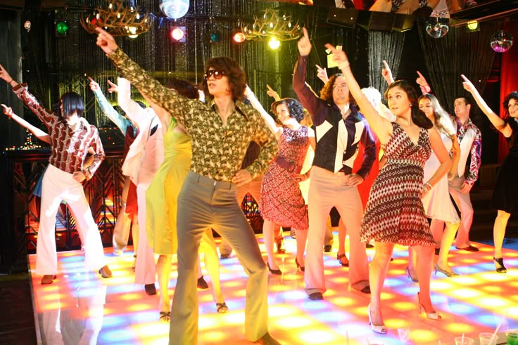 a group of young people dancing on a dance floor with disco balls in the background