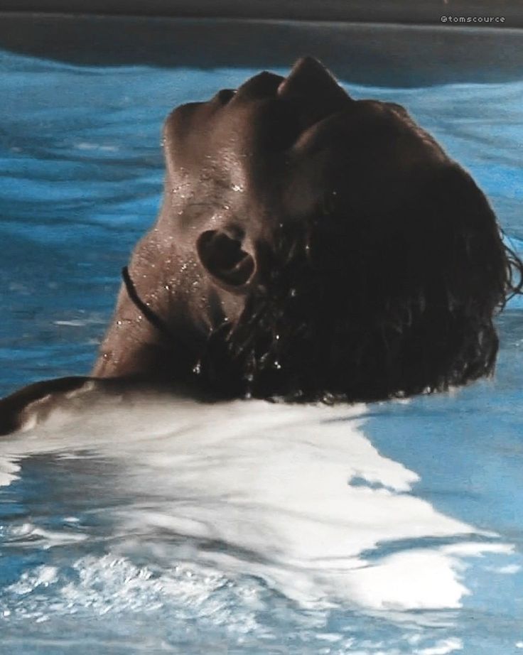 a person swimming in a pool with their head above the water's surface and his eyes closed