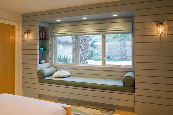 a bedroom with a large window seat next to a bed and book shelf on the wall