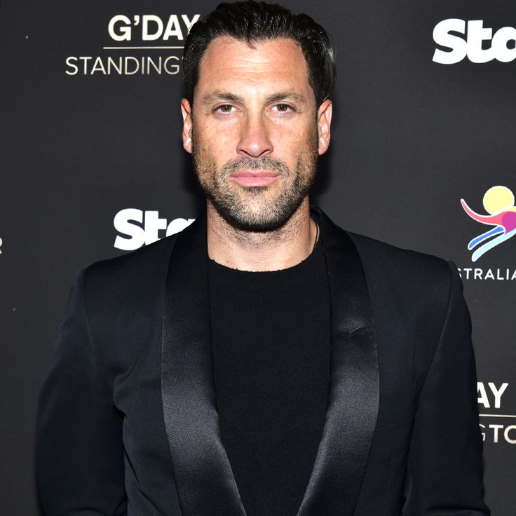 a man wearing a black suit and bow tie standing in front of a red carpet