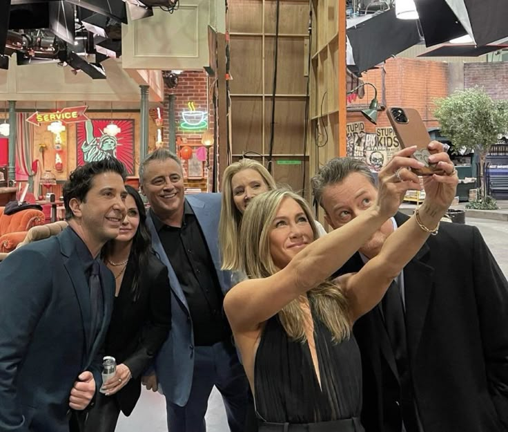 a group of people taking a selfie in front of a tv screen with their cell phones