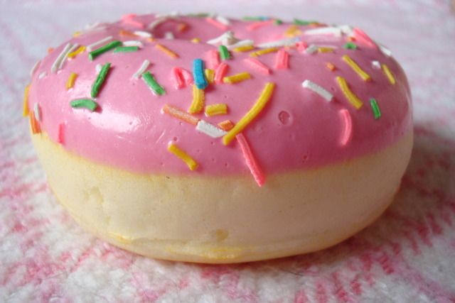 a pink frosted donut with sprinkles on it's side