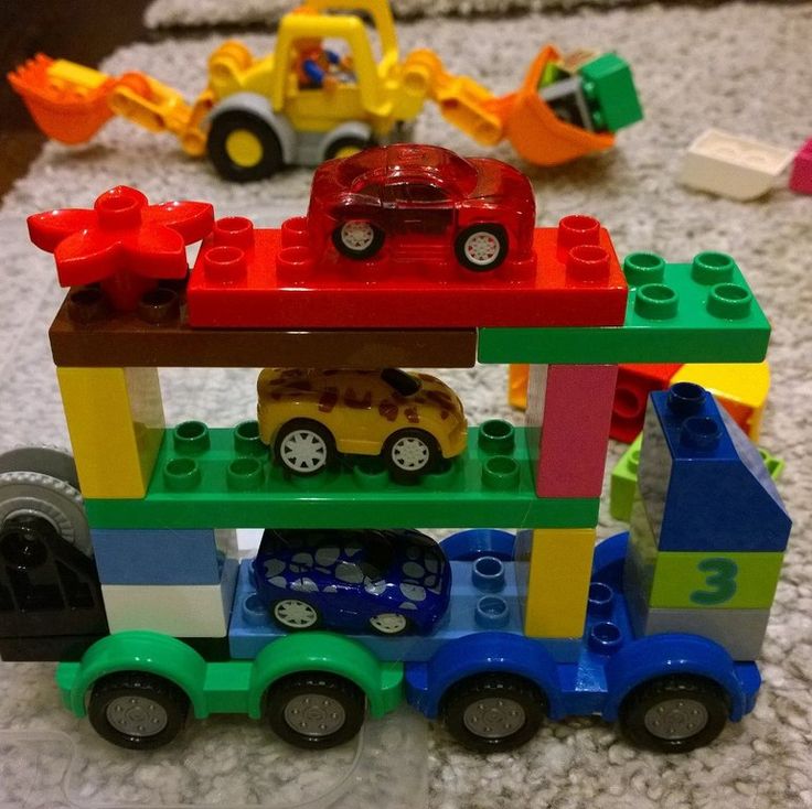 a toy truck carrying lego cars on top of a rug