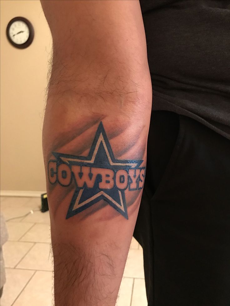 a man with a tattoo on his arm that has the word cowboys painted on it