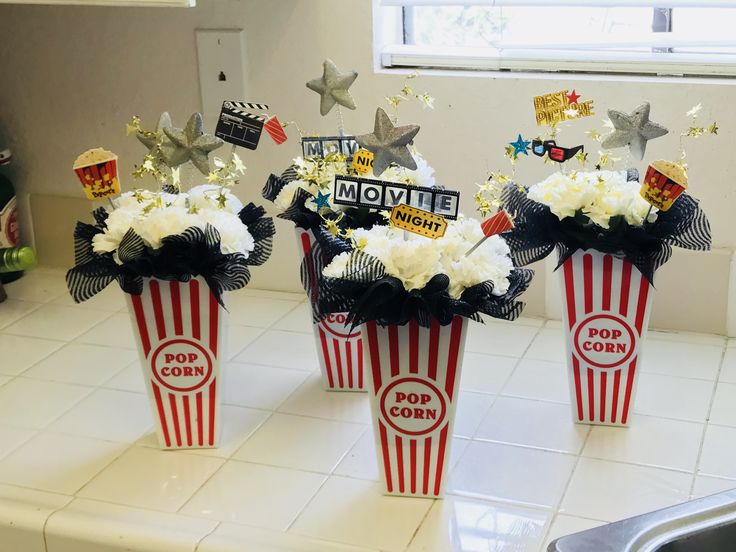 three red and white striped popcorn buckets filled with flowers on a kitchen counter top