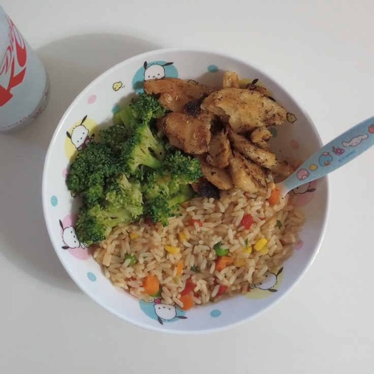 a white bowl filled with rice, broccoli and chicken next to a drink