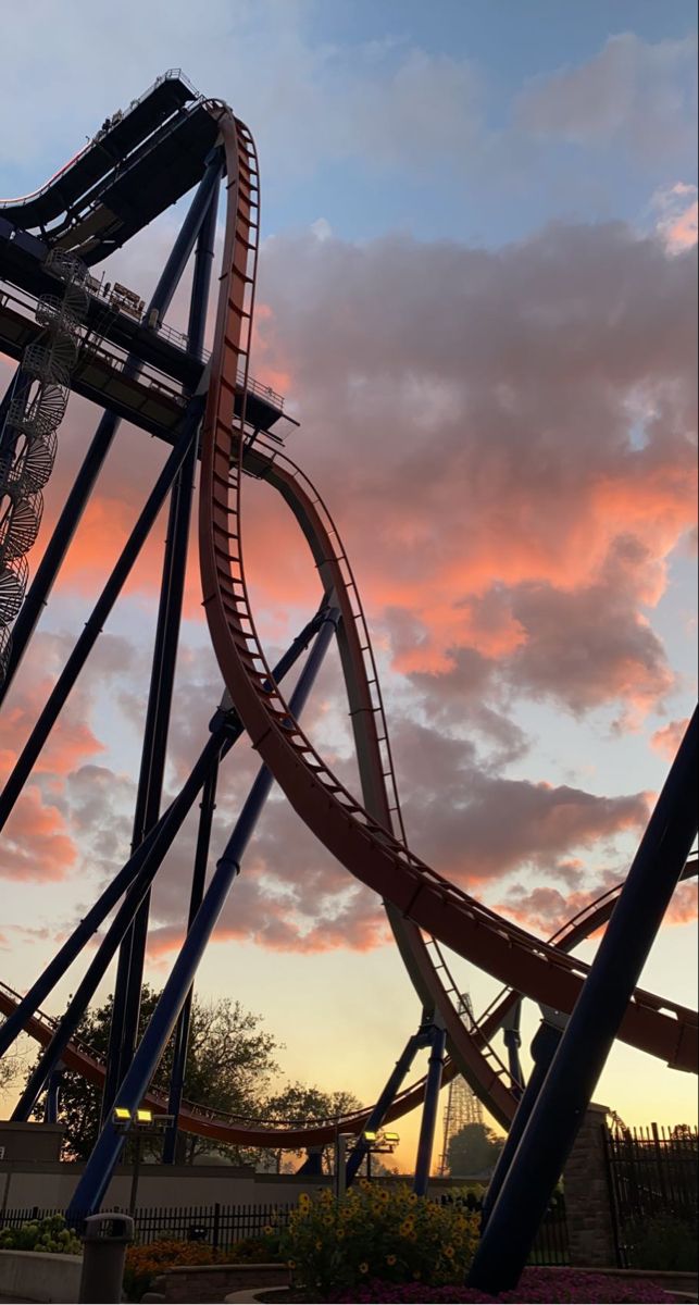 a roller coaster at sunset with clouds in the background