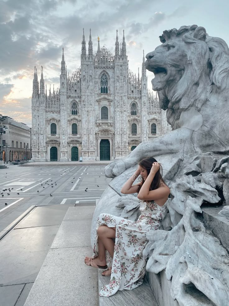 a woman sitting on a lion statue in front of a cathedral