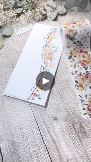 an open gift box with flowers on it next to a white card and flower bouquet