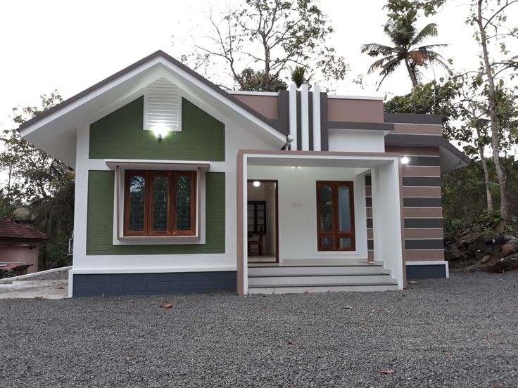 a small green and white house sitting on top of gravel