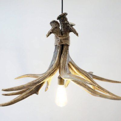 a light fixture made out of antler and wood with two people standing on it